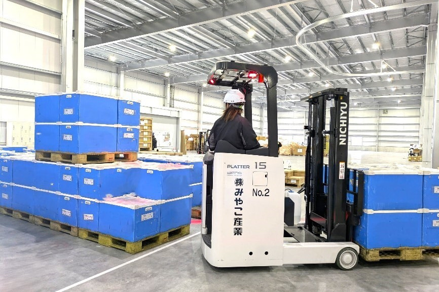 フォークリフトで荷物を運ぶ男性